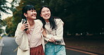 Japanese women, friends and mobile phone for bonding together, walking or outdoor with happiness. Female people, embrace and smile on tech for memory, relax and conversation in park, garden or nature