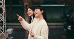 Friends, walking and talking for street market, bonding and conversation with celebration in Japan at night together. Women, outdoor and happy in Tokyo for culture, festival and travel with pointing