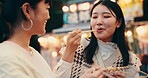 Friends, food and eating for street market, bonding and conversation with celebration in Japan at night together. Women, talking and laughing in Tokyo for culture, festival and community with travel