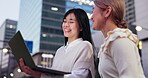 Buildings, city and laptop with business women outdoor together for collaboration or research. Computer, conversation and smile of happy Japanese people in urban town at night for graphic design