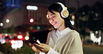 Woman, headphones and phone at night in city, scroll website and streaming online for playlist. Female person, relax and outdoor music for peace in Japan, browse social media and internet for sound