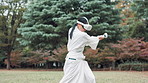 Aikido, controller and virtual reality with Japanese woman in forest for metaverse exercise or training. Cyberspace, practice and VR headset with Ninja person outdoor in nature for culture or skill