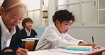 Boy, child and writing in classroom for education with school kids, assessment or test for development. Student, books and notes for exam, knowledge and learning for scholarship at academy in Japan