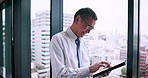 Happy man, tablet and typing at window for business, investment opportunity or company feedback in office. Mature investor, tech or smile in Japanese agency for planning, problem solving or checklist