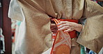 Person, back and fashion designer with belt for kimono, waist or band at clothing boutique or store. Closeup, hands and japanese fabric with tradition or culture for heritage at tailor or seamstress