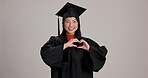 Education, graduation and heart hands with Japanese woman in studio on white background for success. Face, love and smile of happy college or university student in cap and gown as proud graduate