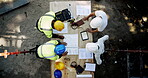 Collaboration, engineering and meeting with construction worker team on building site from above. Architecture, infrastructure and planning with industrial people at table for design discussion