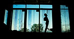 Man, tired or back pain on construction site for building, fatigue or wheelbarrow in silhouette. Worker, tools or injury at worksite for overworked, accident or stretching for muscle relief in shadow