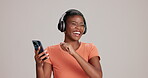 Black woman, studio and smartphone with dancing on headphones for streaming music on white background. Female person, isolated and happy on website for subscription with playlist, audio and song