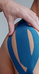 Hands, physiotherapy and tape on shoulder for treatment, recovery and healing for injury. Athlete, therapist and plaster in practice for kinesiology, fitness improvement and mobility in sports person
