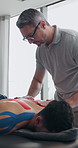 Mature man, physiotherapist and back with patient for muscle recovery, therapy or physical healing. Male person, therapist and client lying on bed with tape for pain relief or relaxing treatment