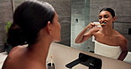 Woman, brushing and teeth with mirror in bathroom for dental hygiene, cleaning or grooming at home. Female person, hygienist or reflection with toothbrush for routine, oral or mouth and gum care