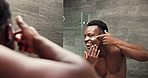Black man, mirror and face cream for bathroom, skincare and morning grooming with moisturizer for natural shine. Guy, reflection and dermatology with sunscreen for anti aging, beauty and skin glow