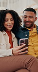 Couple, phone and relax on sofa with smile, reading or conversation for post, chat or scroll on web in home. People, man and woman with smartphone, happy and talking with mobile app on couch in house