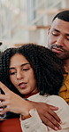 Couple, phone and relax on sofa with hug, care and conversation with love, reading and scroll web in home. People, man and woman with embrace, smartphone and talking with mobile app on couch in house