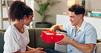 Couple, love and gift on home for Valentines day, celebration and romantic gesture on sofa. Happy woman, man and box in lounge with birthday surprise, present or relationship milestone with thank you