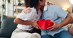 Couple, hug and gift on home for celebration, Valentines day and romantic gesture on sofa. Happy woman, man and box in lounge with birthday surprise, present or relationship milestone with thank you