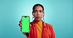 Hand, phone and green screen with woman in studio, face and mock up space with ui by blue background. Girl, person and smartphone with blank display, online and user experience on web in Costa Rica