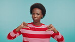Thumbs down, no and face of black woman in studio for mistake, wrong choice and vote. Negative reviews, dislike and feedback with person on blue background for poor ratings, fail and rejection