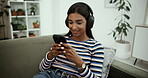 Phone, music and happy woman with headphones in home for jazz album, song and listening to radio. Mobile, audio and girl on sofa to relax, scroll app and streaming service or typing for subscription