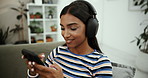 Mobile, music and happy woman with headphones in home for jazz album, song and listening to radio. Phone, audio and girl on sofa to relax, scroll app and streaming service or typing for subscription