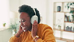 Headphones, dancing and black woman in living room in house listening to music, radio or playlist. Happy, living room and African female person with audio tech for streaming album online in apartment