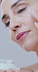 Beauty, woman and skincare with cream application for firm skin, collagen treatment or hyaluronic acid. Mature person, lotion or cosmetics product for anti aging, retinol or glow on studio background