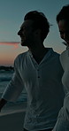 Walking, night or couple with smile at beach for valentines day, love or romance in interracial relationship. Sunset, happy or people bonding on holiday for romantic honeymoon, care or travel date