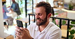 Phone, smile and text message with man in coffee shop for communication, contact or social media. App, laughing and meme with happy customer in internet cafe or restaurant for hospitality or service