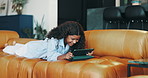 Laughing, tablet and girl on sofa in home watching comedy movie, show or video on weekend. Happy, relax and female teenager streaming funny film on app with digital technology in living room in house