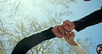 Business people, fist bump or meeting with teamwork below blue sky for unity or solidarity at park. Low angle, group or employees with hands in union for commitment, mission or collaboration together