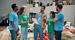 Volunteer, group and people in warehouse for donation, inventory discussion or food bank. Charity, help or community service at storehouse with happy leader planning stock on grocery checklist at ngo