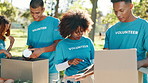 Outdoor, donation and volunteers packing cardboard boxes for community outreach with food drive. Helping, happy and group of NGO workers with parcel for charity event with nonprofit service in nature