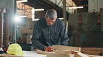Mature man, carpenter and measuring tape for wood, drawing or design process at workshop. Person, tools and pencil with plank, paper and creative for furniture, manufacturing or industry in factory