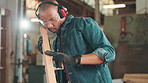 Carpentry, woodwork and black man in workshop for sanding wood for furniture, manufacturing or lumber production. Construction, factory and carpenter with planks, timber and board for restoration