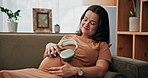 Calm, pregnant woman and relax with headphones on stomach for music, comfort or soothing on sofa at home. Female person, smile or earphones with baby belly for happy relief, zen or maternity at house
