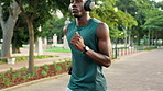 Headphones, running and black man in park for health, wellness and fitness. Radio, podcast and African athlete with endurance training, exercise and workout for cardio and jog outdoors in nature