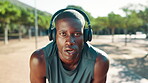 Runner, tired and man with headphones, sweating and playlist for workout in morning or outdoor. Breathing, break and black person with fatigue, exhausted and listening to music with tech and exercise