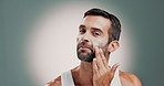 Skincare, face and man with moisturizer in studio for health, wellness and natural facial routine. Face cream, portrait and person with dermatology treatment with spf or sunscreen by gray background.