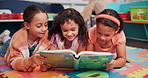 Education, happy and children with book in classroom for learning, development or story time. Friends, relax and girl students reading novel on floor mat for literacy knowledge at elementary school. 