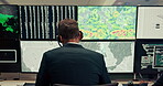 Man, computer and screen with maps in control room, monitor weather and climate change. Back, meteorologist and headset with alert for satellite update, study storm pattern and disaster surveillance
