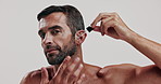 Skincare, serum and face of man in studio for natural, health and facial routine for glow. Portrait, confident and male person from Brazil with hydration dermatology treatment by white background.