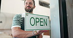 Small business, man and open sign by cafe door for start of day, customer welcome and message to public. Storefront, signage poster and friendly barista with greeting for hospitality and advertising