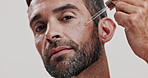 Skincare, natural and face of man with serum in studio for natural, health and facial routine for glow. Portrait, confident and male person with hydration dermatology treatment by white background.