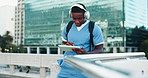 Headphones, doctor and student with tablet in city studying for clinical exam or test. Education, technology and African male healthcare intern listening to music and reading online textbook in town