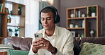 Phone, relax and man with headphones on sofa in morning with contact for texting online with app. Networking, typing and male person in lounge with communication, cellphone and audio tech for music.