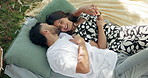 Couple, date and happy in park with kiss, bonding and point with cloud watching. People, holding hands and outdoor for relationship development, weekend relax or smile for love and anniversary picnic