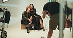 Photography, set and photographer with couple on chair in studio with production team for creative magazine. Fashion, equipment and influencers posing on chair for portfolio photoshoot with agency.