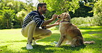 Man, dog and treat with snack in nature for walk, run or game of fetch at outdoor park. Male person, owner and pet or Labrador animal with food for reward, love or care in forest for training