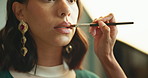 Studio, makeup artist and lipstick for model, set and preparing for photoshoot, glow and cosmetics. Production, hand and makeover with brush for woman, behind the scenes and people with equipment